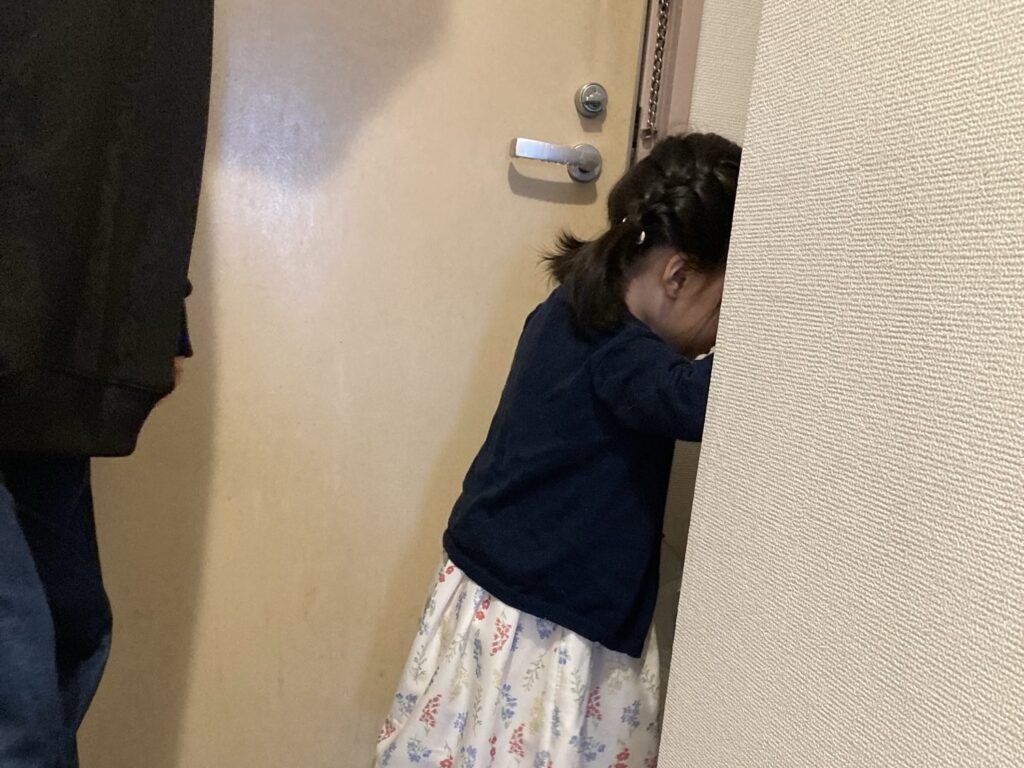 娘がドアの内側で立っている